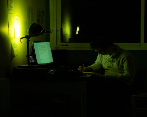 Person adjusting warm light settings on a laptop screen during evening hours
