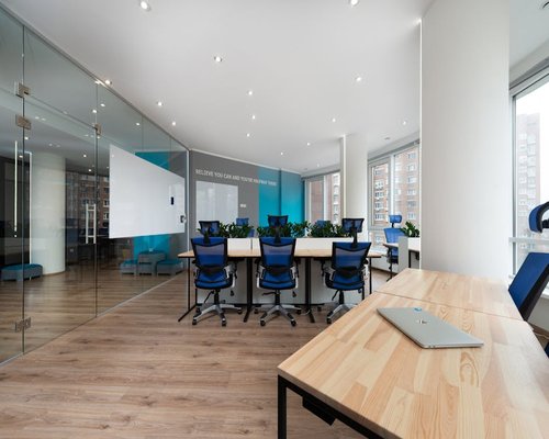 Bright conference room with wide glass windows and organized desk layout